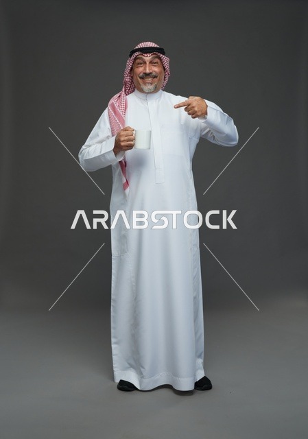 رجل سعودي مسن يحمل كوب قهوة في الاستوديو