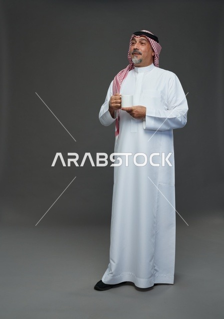 رجل سعودي مسن بالزي التقليدي يحمل كوب قهوة أبيض