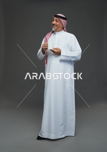 رجل سعودي مسن يحمل كوب قهوة في الاستوديو