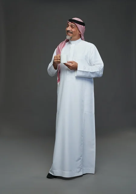 رجل سعودي مسن يحمل كوب قهوة في الاستوديو