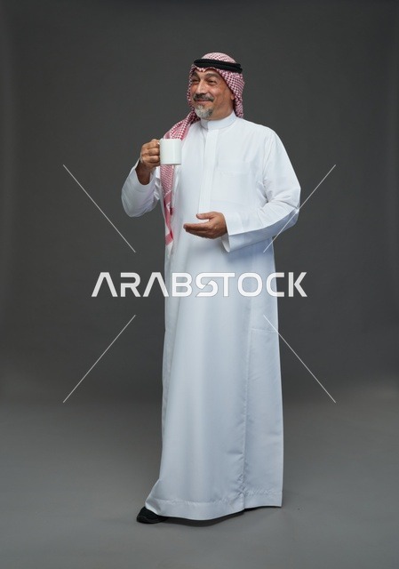 رجل سعودي مسن يحمل كوب قهوة في الاستوديو