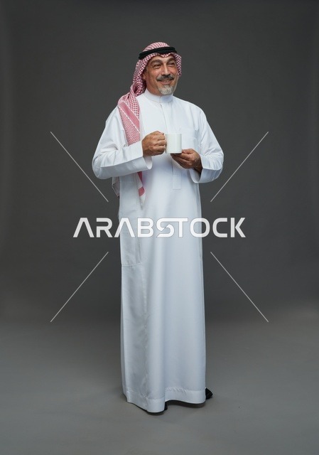 رجل سعودي مسن يحمل كوب قهوة في الاستوديو
