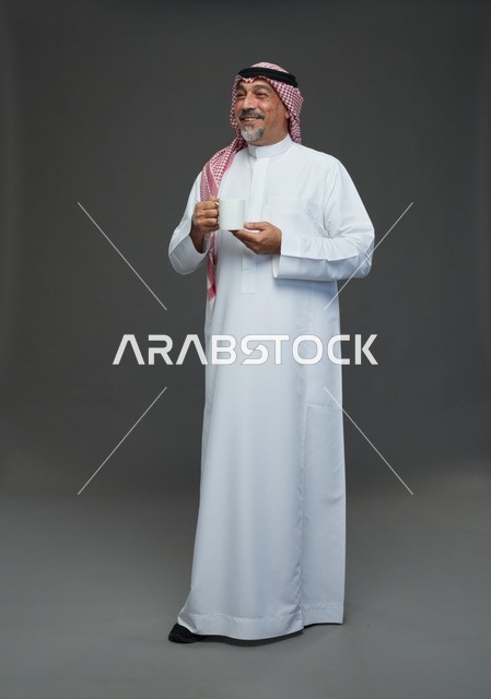 رجل سعودي مسن يحمل كوب قهوة أبيض في الاستوديو