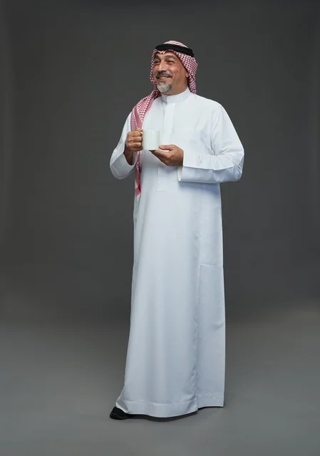 رجل سعودي مسن يحمل كوب قهوة أبيض في الاستوديو