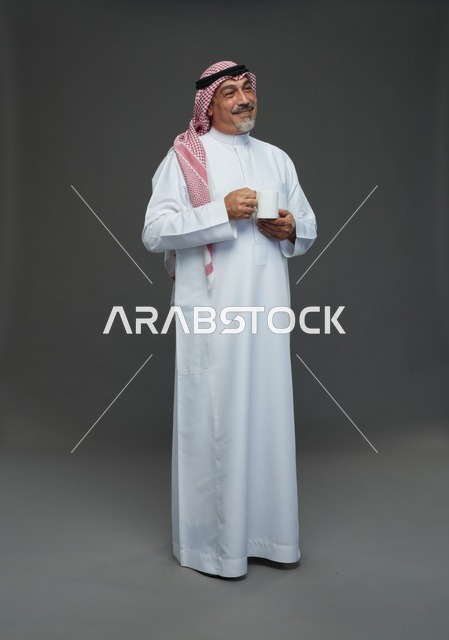 رجل سعودي مسن يحمل كوب قهوة أبيض في الاستوديو