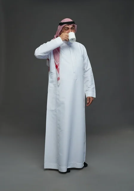 Senior Saudi Man in Traditional Dress Drinking from Mug