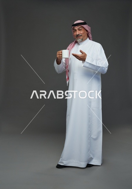 رجل سعودي مسن يحمل كوب قهوة في الاستوديو
