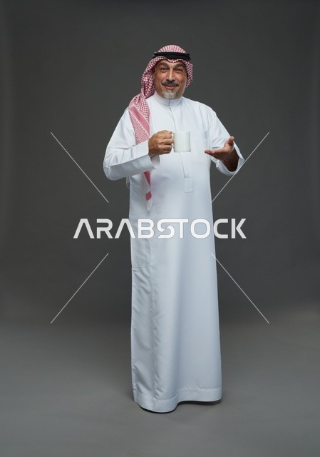 رجل سعودي مسن يحمل كوب قهوة في الاستوديو