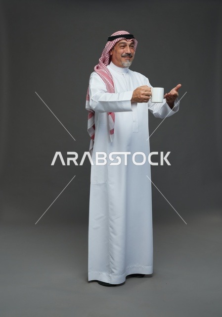 رجل سعودي مسن يحمل كوب قهوة أبيض في الاستوديو