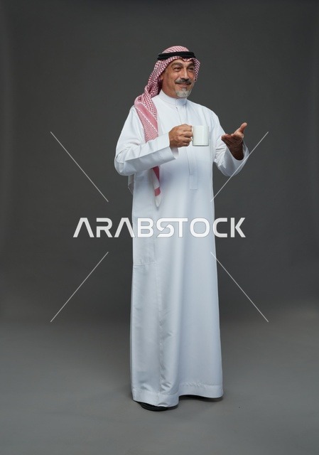 رجل سعودي مسن يحمل كوب قهوة أبيض في استوديو