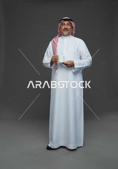 رجل سعودي مسن يحمل كوب قهوة أبيض في استوديو