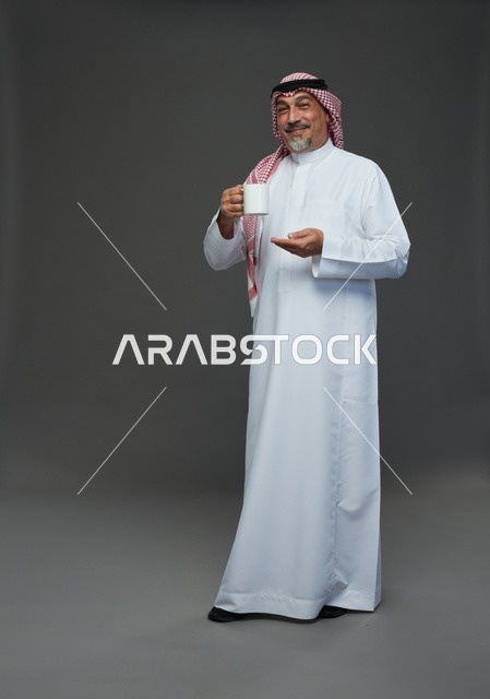 رجل سعودي مسن بالثوب التقليدي يحمل كوب أبيض