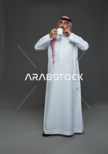 رجل سعودي مسن يحمل كوب قهوة أبيض في استوديو