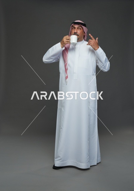 رجل سعودي مسن يحمل كوب قهوة في الاستوديو