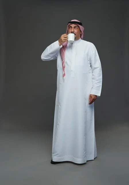 رجل سعودي مسن يحمل كوب قهوة أبيض