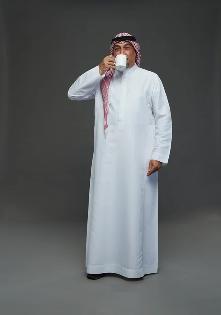 Elderly Saudi Man Drinking From White Coffee Cup