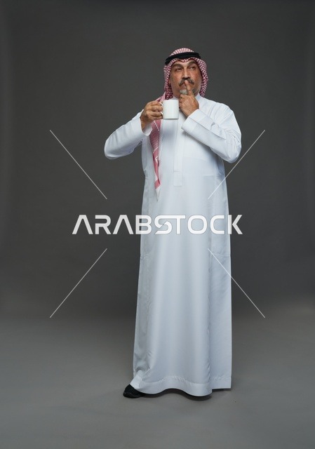 رجل سعودي بالزي التقليدي يحمل كوب قهوة أبيض