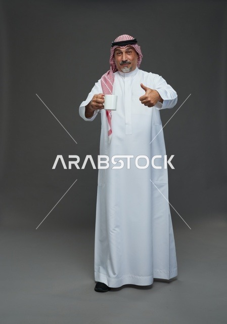 رجل سعودي مسن يحمل كوب قهوة أبيض