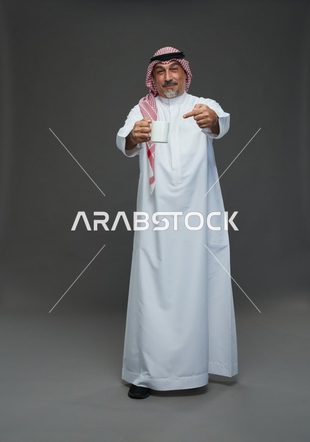 رجل سعودي مسن بالزي التقليدي يحمل كوب قهوة