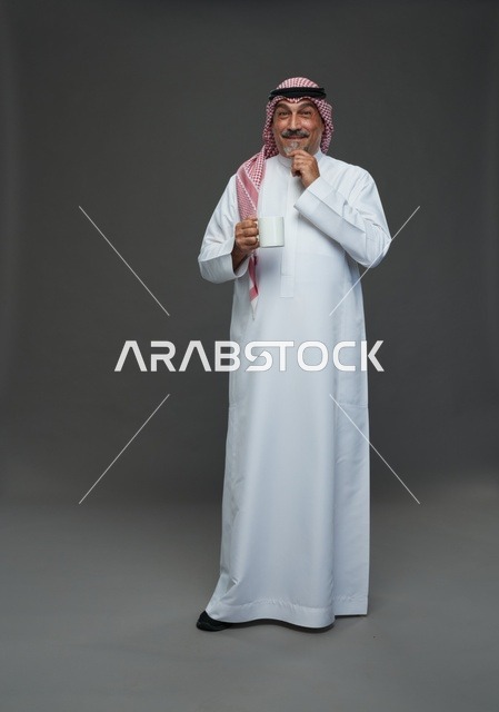 رجل سعودي مسن يحمل كوب قهوة أبيض في استوديو