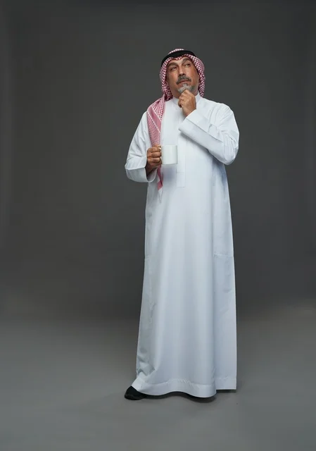 Elderly Saudi man holding a white coffee mug