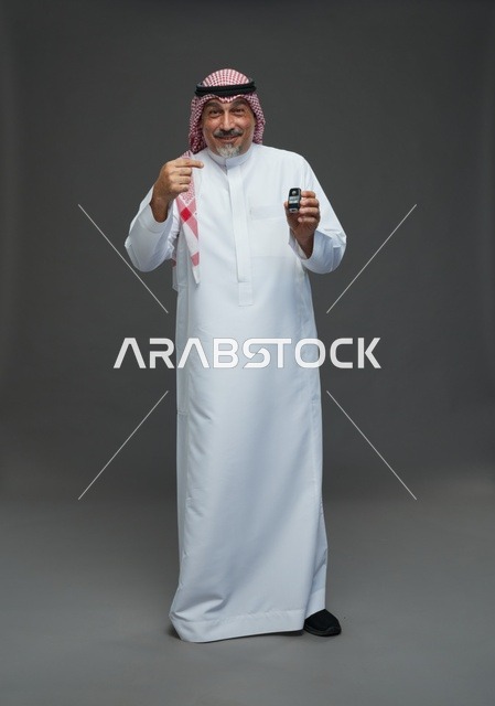رجل سعودي يحمل مفتاح سيارة في الاستوديو