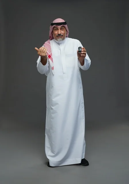 Saudi Man Holding Car Key on Gray Background