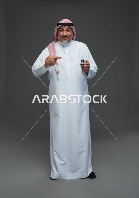 رجل سعودي يحمل مفتاح سيارة ويبتسم