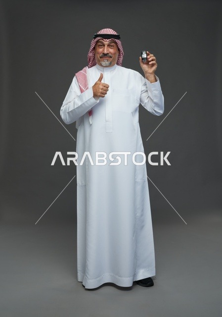 رجل سعودي يحمل مفتاح سيارة وعلامة الإبهام للأعلى