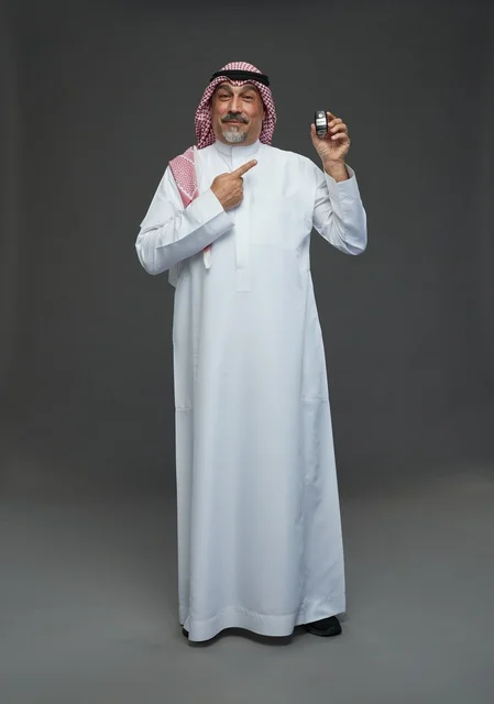 رجل سعودي يحمل مفتاح سيارة بابتسامة في استوديو تصوير