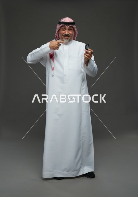 رجل سعودي يحمل مفتاح سيارة في الاستوديو