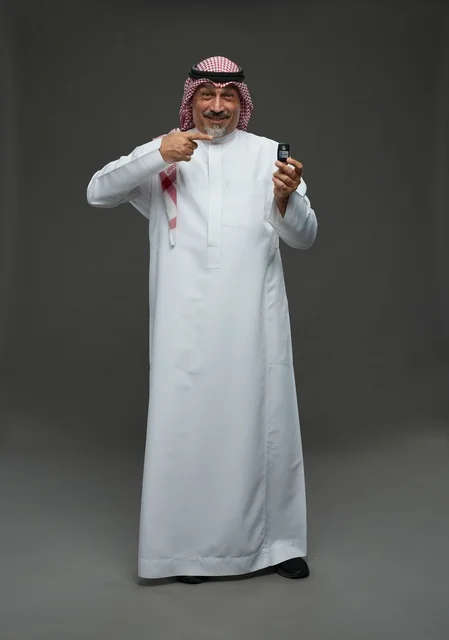 رجل سعودي يحمل مفتاح سيارة في الاستوديو
