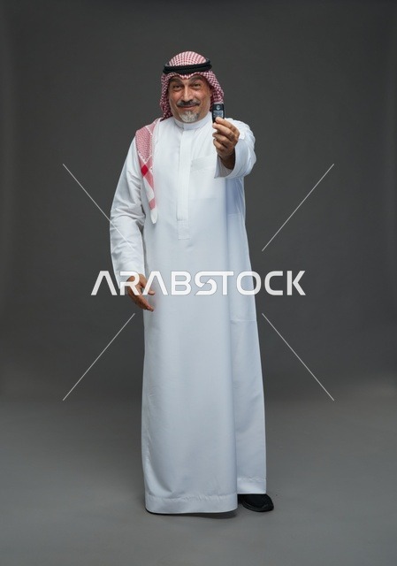 رجل سعودي يحمل مفتاح سيارة أمام خلفية رمادية