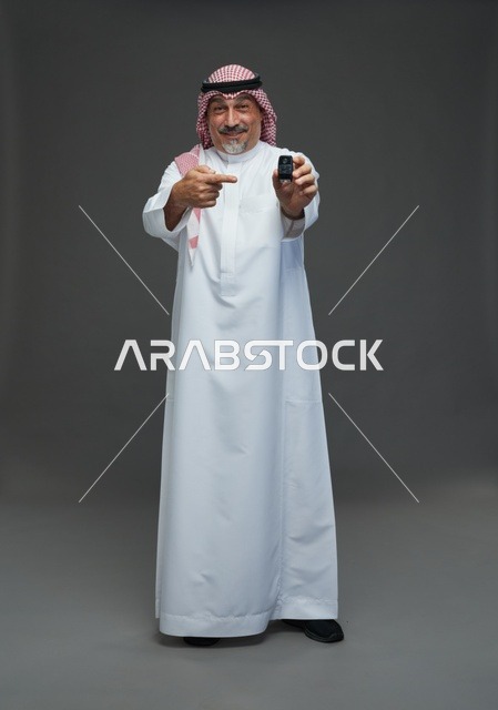 رجل سعودي يحمل مفتاح سيارة ويبتسم