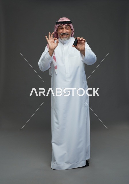 رجل سعودي يحمل مفتاح سيارة مع إشارة الموافقة