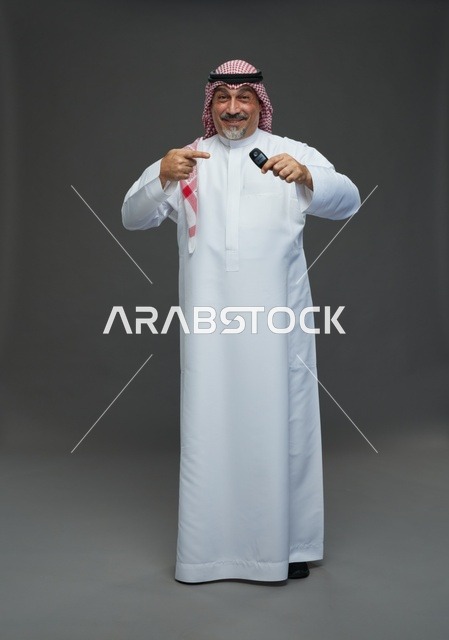 رجل سعودي يحمل مفتاح سيارة في لقطة استوديو