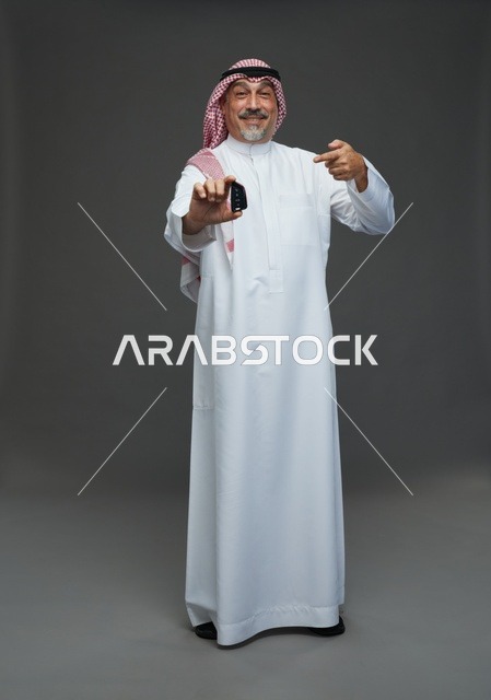 رجل سعودي يحمل مفتاح سيارة في الاستوديو لقطة كاملة