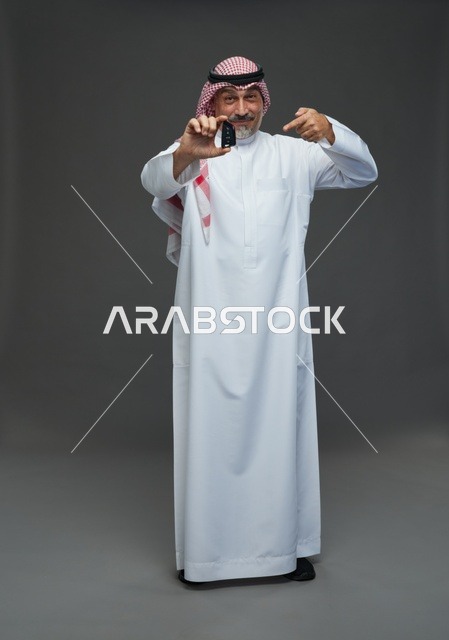 رجل سعودي يحمل مفتاح سيارة في الاستوديو