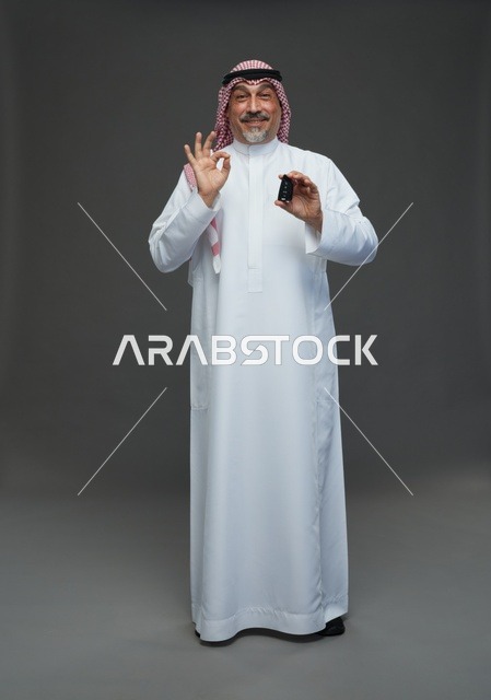 Saudi Man Holding Car Key with OK Gesture Studio Portrait