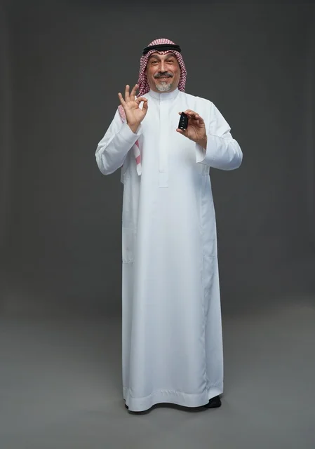 رجل سعودي يحمل مفتاح سيارة ويقوم بإشارة الموافقة