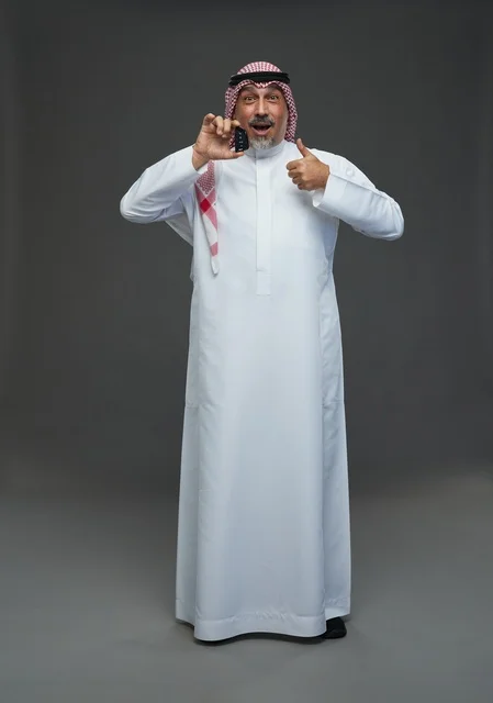 رجل سعودي يحمل مفتاح سيارة مع إيماءة الإبهام