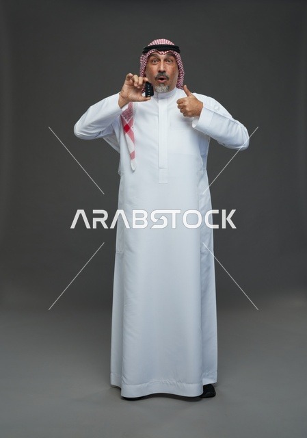 رجل سعودي يحمل مفتاح سيارة مع إيماءة النجاح