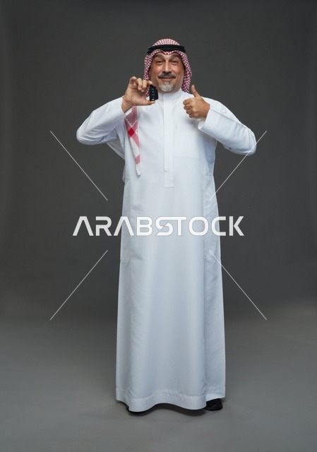 رجل سعودي يحمل مفتاح سيارة ويبتسم