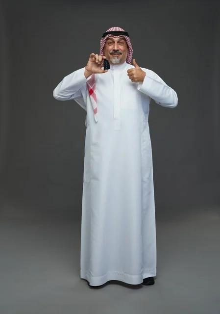 رجل سعودي يحمل مفتاح سيارة ويبتسم