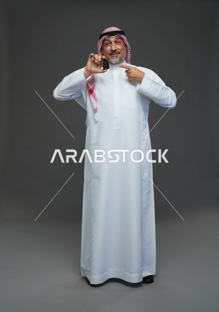 رجل سعودي يحمل مفتاح سيارة ويبتسم في الاستوديو