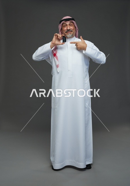 رجل سعودي يحمل مفتاح سيارة في الاستوديو