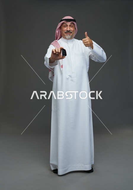 رجل سعودي يحمل مفتاح سيارة ويبتسم