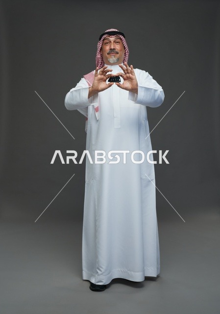 رجل سعودي يحمل مفتاح سيارة بخلفية رمادية
