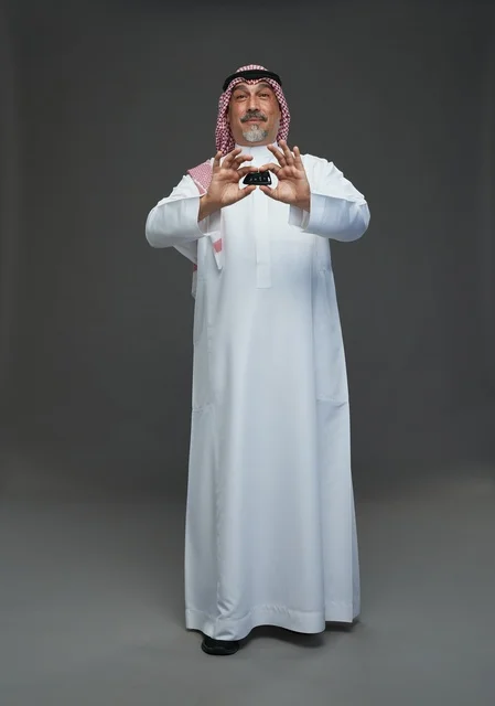 رجل سعودي يحمل مفتاح سيارة بخلفية رمادية