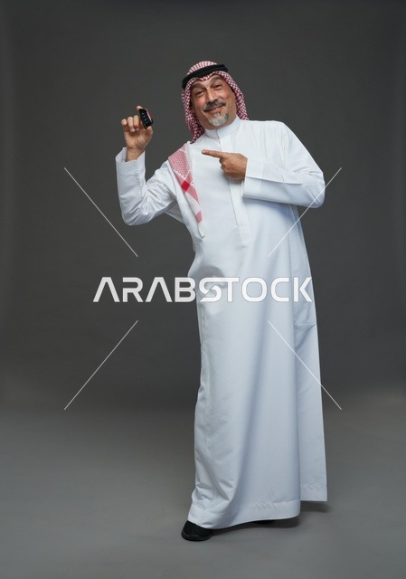 رجل سعودي بالزي التقليدي يحمل مفتاح سيارة